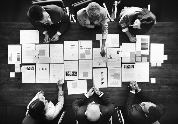 Business team collaborating around a table covered with plans and documents