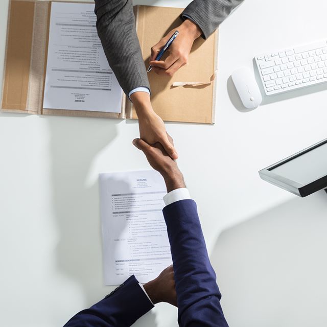 Business handshake over a desk with signed documents