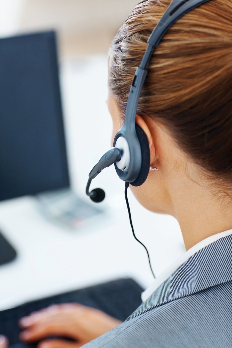 Customer support agent wearing a headset while working at a computer